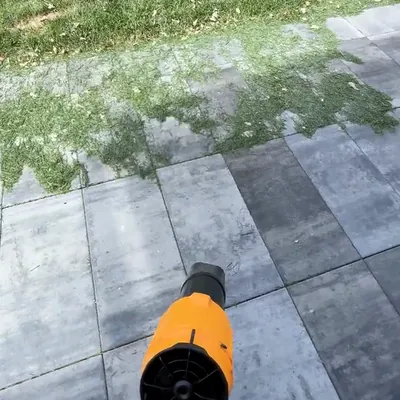 The SuperLeafBlower pushing grass clippings off a paved patio