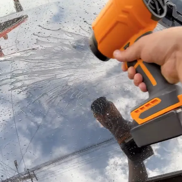 Hand holding the SuperLeafBlower over a wet black car hood, blowing the water off